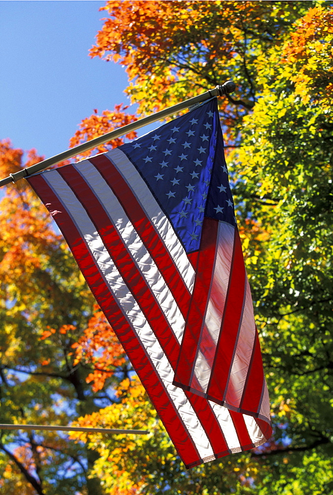 Autumn maple leaves in October, part of the beautiful New England fall display, and the Stars & Stripes, round the band stand on the Town Common of Hopkinton, starting point of the Boston Marathon, Massachusetts, USA