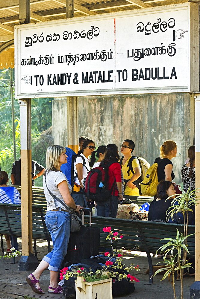 Foreign travellers await the popular Colombo to Badulla train at the railway station at Peradeniya, near Kandy, Sri Lanka, Asia