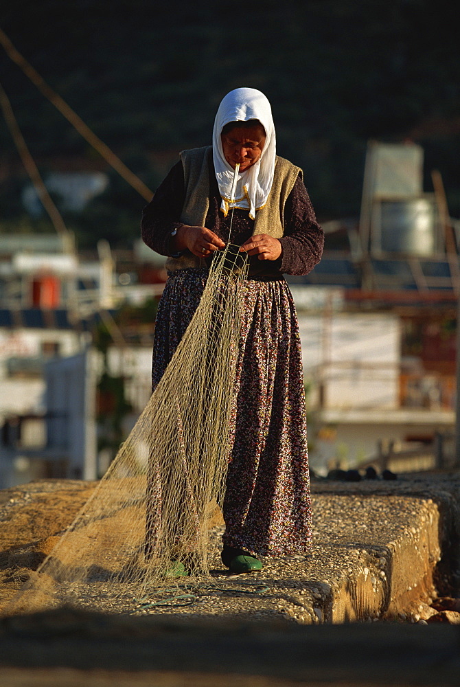 Woman in traditional baggy trousers mending a fishing net, Kas, Anatolia, Turkey, Asia Minor, Eurasia