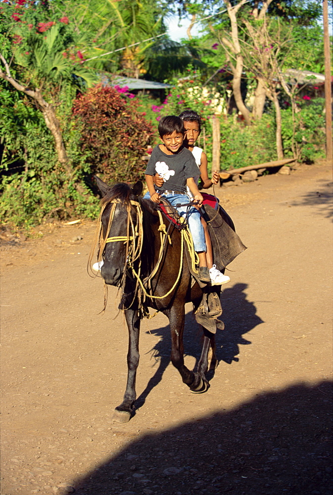 Two children on horseback at Balgue on the slopes of Volcan Maderas in the east of the island of Omotepe, Lake Nicaragua, Nicaragua, Central America