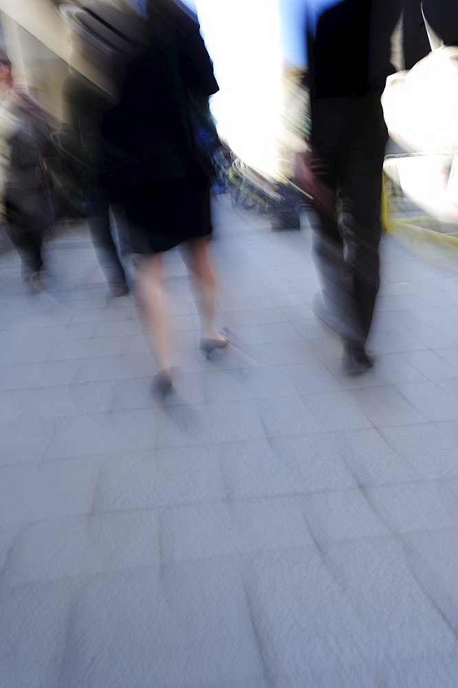 Man and woman in business clothing walking on a sidewalk, motion blur