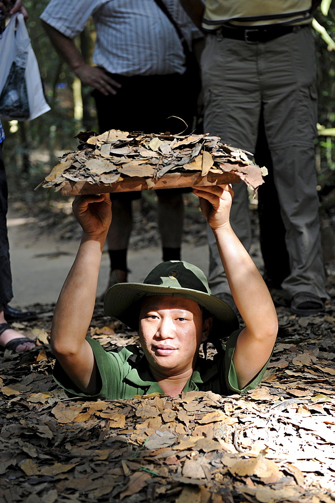 Vietnamese man descending into the tunnel system of the Vietcong in Cu Chi, South Vietnam, Vietnam, Southeast Asia, Asia