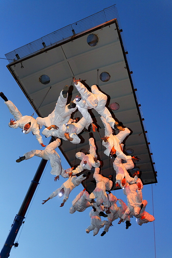 White-clad trapeze artists hanging upside down from a platform in the air, Global Rheingold, open-air theater by La Fura dels Baus, Duisburg-Ruhrort, Ruhrgebiet area, North Rhine-Westphalia, Germany, Europe