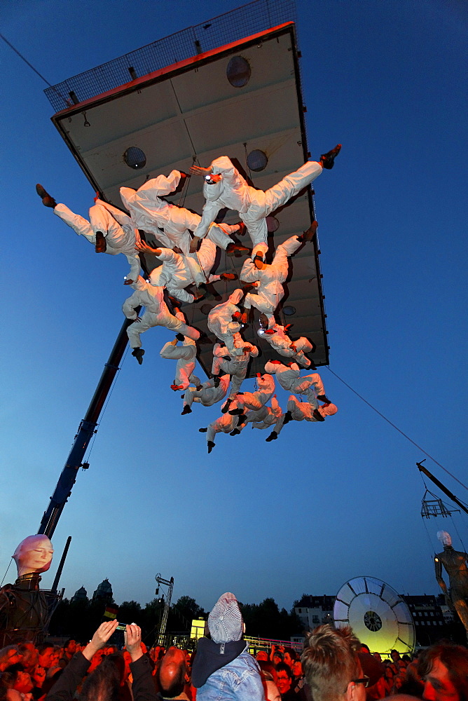 White-clad trapeze artists hanging upside down from a platform in the air, Global Rheingold, open-air theater by La Fura dels Baus, Duisburg-Ruhrort, Ruhrgebiet area, North Rhine-Westphalia, Germany, Europe