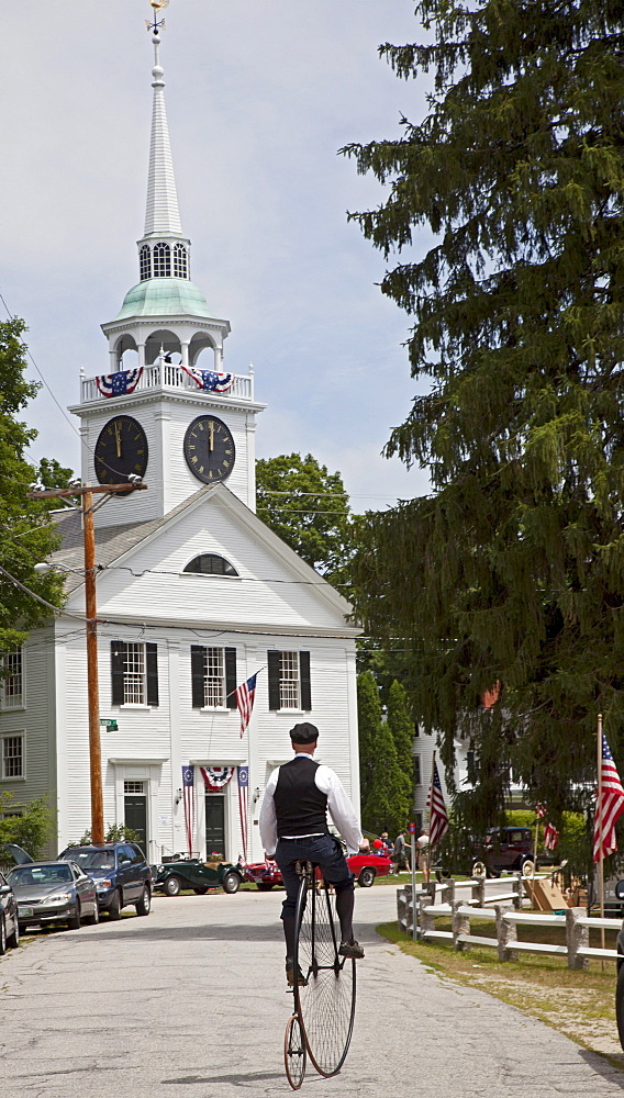 A man rides an antique high wheel bicycle near the Congregational Church of Amherst following the town's July 4 parade, Amherst, New Hampshire, USA