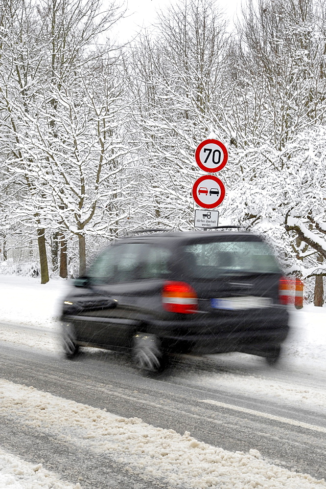 Car on a snow-covered road in winter, slip hazard, warning sign, prohibition sign, blur