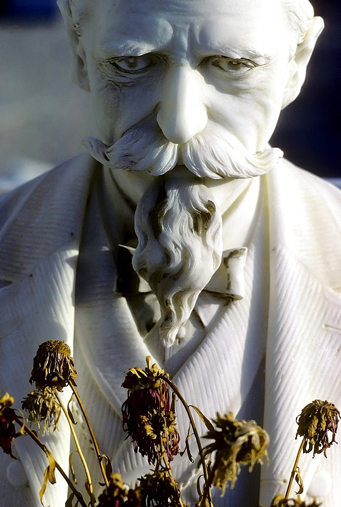 Sad old man with a moustache and a goatee beard with dried flowers, sculpture on a grave, historic cemetery of Nice, France, Europe