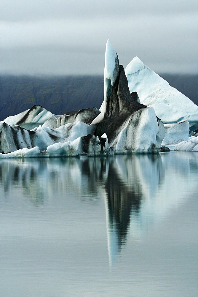 Floating icebergs, coloured with black lava ash, in the Joekulsarlon glacier lagoon of the Vatnajoekull Glacier, Iceland, Europe