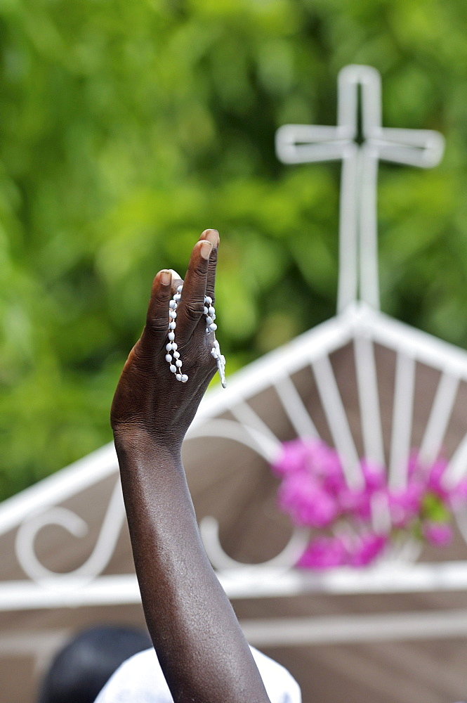 Raised hand with rosary in front of a cross, parish of Sacre Coeur, Turgeau district, Port-au-Prince, Haiti, Caribbean, Central America