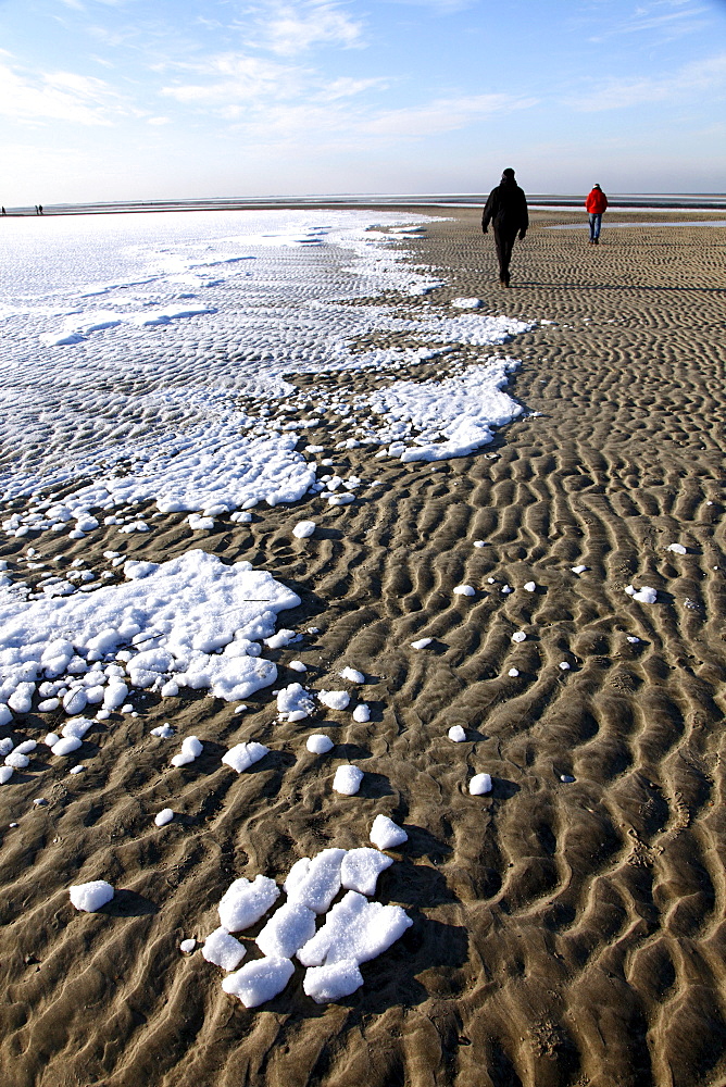 People walking along the snow-covered beach on the East Frisian North Sea island of Spiekeroog, Lower Saxony, Germany, Europe