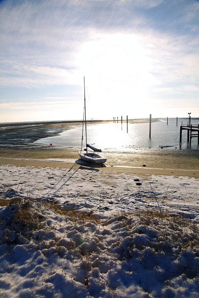 Bay in the Wadden Sea with a sailing boat, snow-covered beach on the East Frisian North Sea island of Spiekeroog, Lower Saxony, Germany, Europe