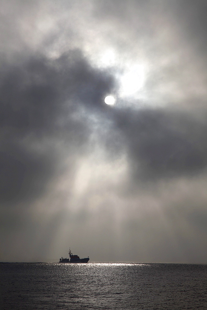 Rescue boat of the German sea rescue association cruising on the East Frisian Wadden Sea, dramatic clouds, Spiekeroog island, an island in the North Sea, Lower Saxony, Germany, Europe