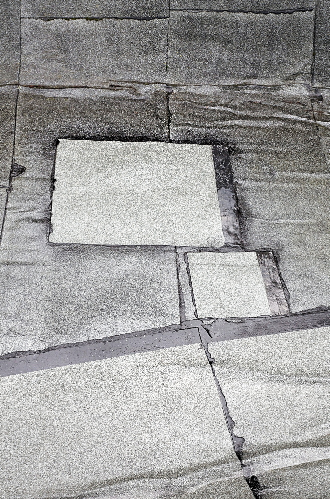 Patched-up, repaired areas on a roof made of roofing felt