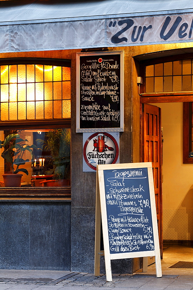 Typical Duesseldorf pub in the historic district, menu board displayed in front of the door, evening mood, Ratinger Strasse street, Duesseldorf, North Rhine-Westphalia, Germany, Europe