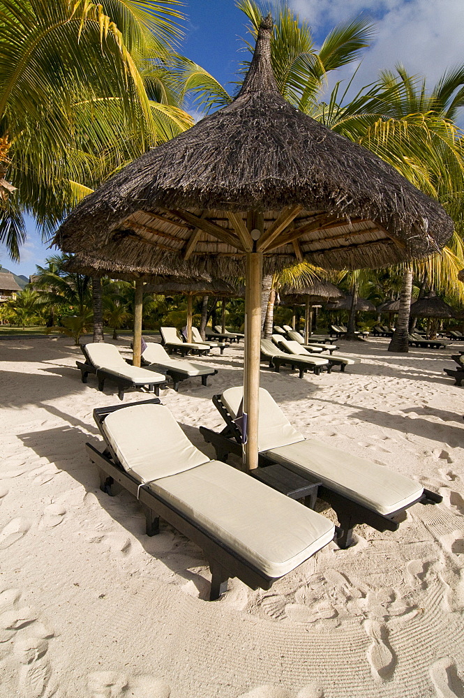 Sunbeds under sunshade on the beach of Le Paradis Hotel, Mauritius, Africa