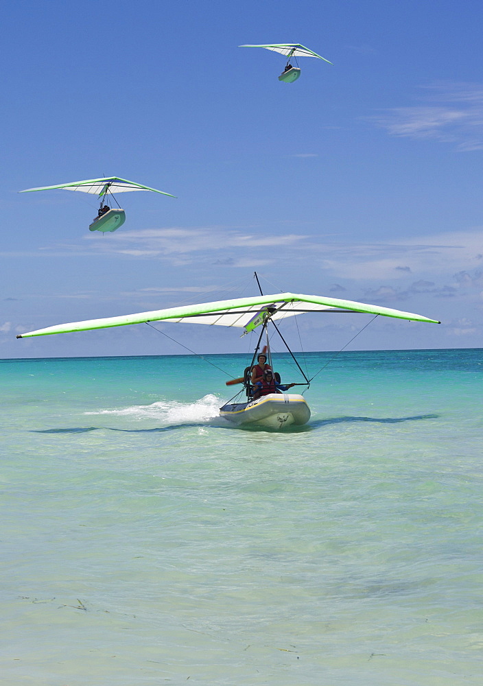 Motorised hang glider landing at sea, with boat, ultralight aircraft, UL trike, Varadero, Cuba, Caribbean, Central America