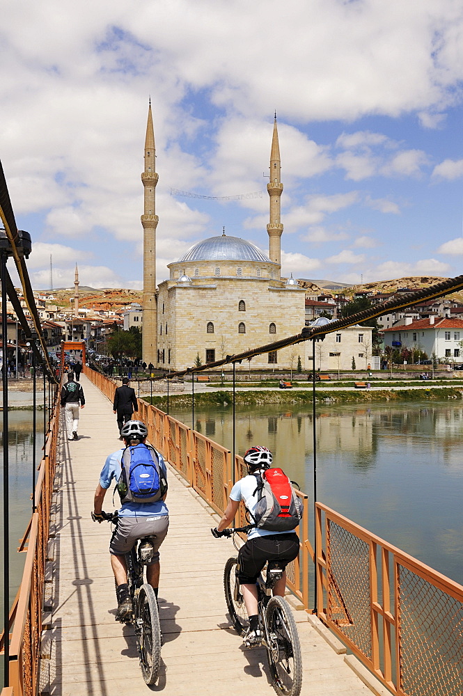 Mountain bikers in front of a mosque, Avanos, Cappadocia, Turkey, Western Asia