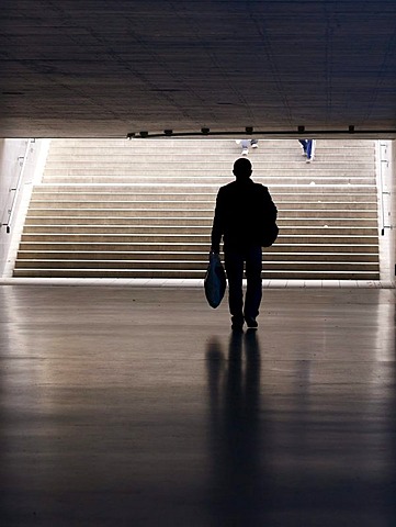 Man carrying a shopping bag in a pedestrian underpass