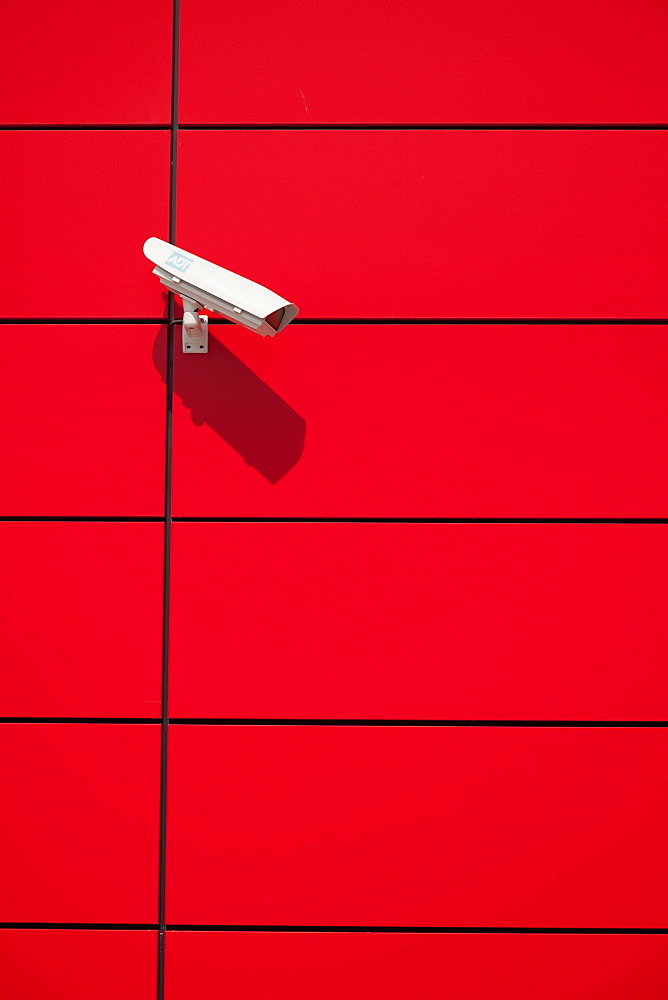 Surveillance camera on a red wall.