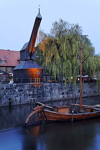 Old crane and replica of a salt ship on the Illmenau river, evening mood, historical salt port, Lueneburg, Lower Saxony, Germany, Europe