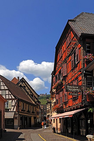 Main street with old Alsatian half-timbered houses, in the distance, the ruins of Ulrichsburg Castle, Grand'Rue, Ribeauville, Alsace, France, Europe