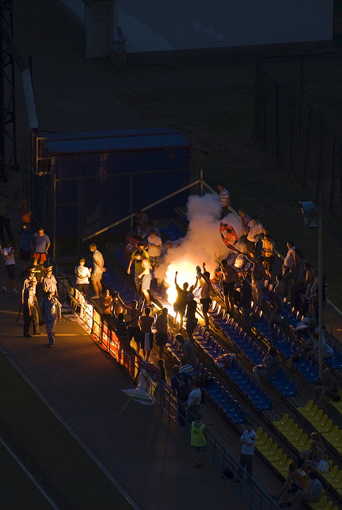 Football fans on tribune lighting fireworks