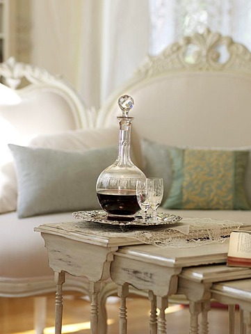 Fine wine carafe with glass on white-painted table, with a stylish sofa