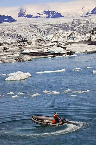 Inflatable boat on Joekulsarlon glacial lake, icebergs with different colours due to the black from volcanic ash, Joekulsarlon, Vatnajoekull, Iceland, Europe