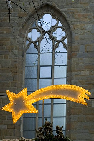 Illuminated Christmas star in front of a stained glass window