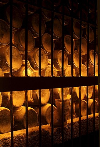 Dusty, wine bottles in storage in an old wine cellar behind iron bars