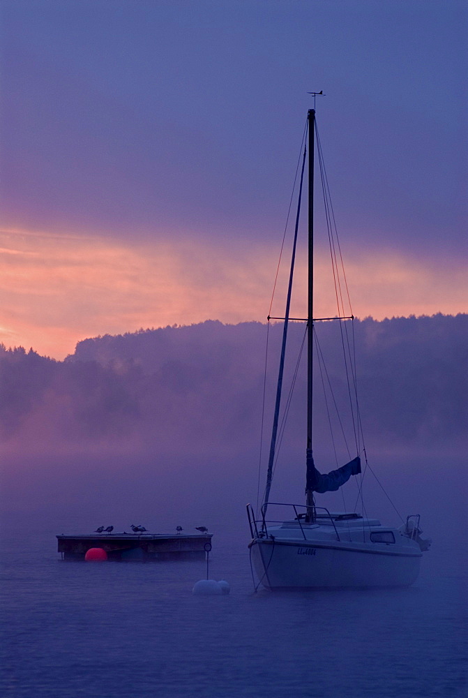 Sun rising behind sailing boats and fog over Ammersee lake, Bavaria, Germany, Europe