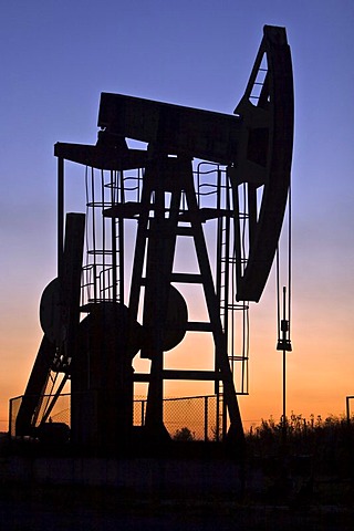 An industrial pumpjack in the sunset, silhouette