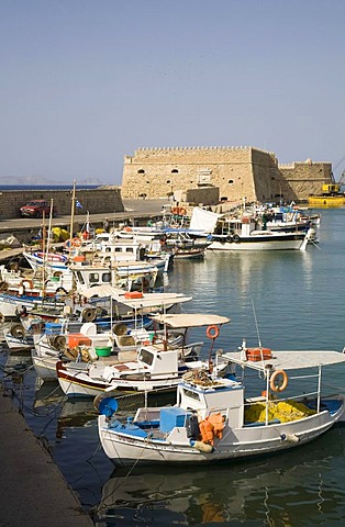 Fishing boats anchoring in the Venetian harbor of Heraklion, behind them the fortress of Kastro Koules in Heraklion, island of Crete, Greece, Europe