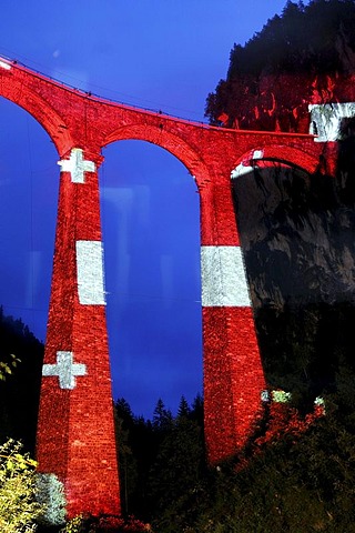 Irrigation water viaduct lit up with the national flag motif to celebrate the acceptance of the "Rhaetische Bahn Railway in Albula/Bernina" as a UNESCO World Heritage Site, Filisur, Graubuenden, Switzerland, Europe