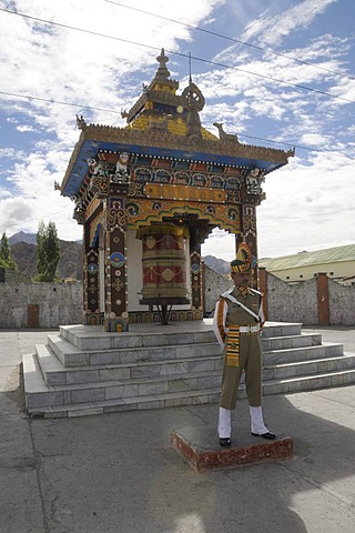 Indian soldier keeping watch in front of a Buddhist prayer wheel, Leh, Northern India, India, Himalayas