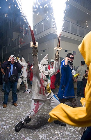 During the Correfoc or Fire Run, hooded Fire Devils run the streets of Spanish towns brandishing fireworks, Altea, Costa Blanca, Spain