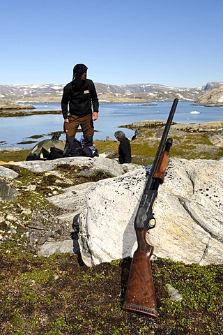 Trekker checking his shotgun for defence against polar bears, Ikasartivaq Fiord, East Greenland