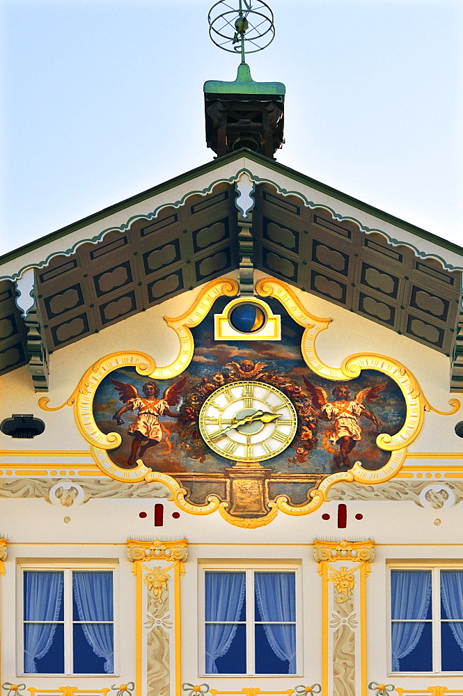 Building facade brightly painted with golden angel motifs surrounding a clock (lueftlmalerei), Bad Toelz, Bavaria, Germany