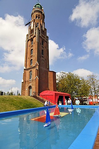 Old lighthouse and senior citizens playing with remote-controlled model ships, Bremerhaven, Bremen, Germany