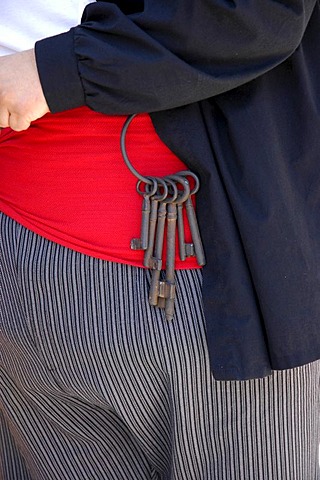 Bunch of keys with large keys hanging on the red sash of a large man, cummerbund