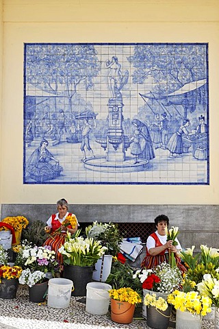 Woman selling flowers behind a azulejo (glazed tile) with a market scene, Funchal, Madeira, Portugal