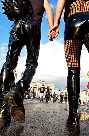 Fetish couple holding hands while walking to Brandenburg Gate during the Loveparade in Berlin, Germany