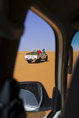 Glimpse out of the window of a vehicle to a pickup Toyota jeep Ubari Sand Sea Libya