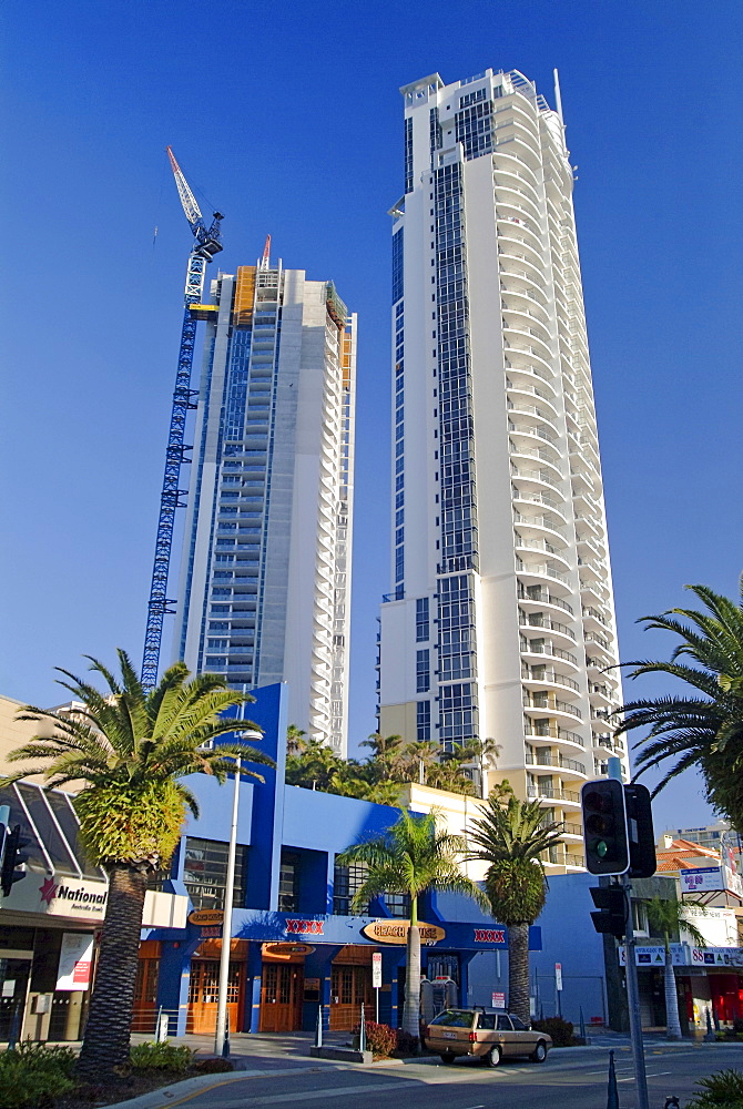 Palm-lined commercial street, high-rises and crane working on the upper stories of a building site, Surfer's Paradise, Queensland, Australia