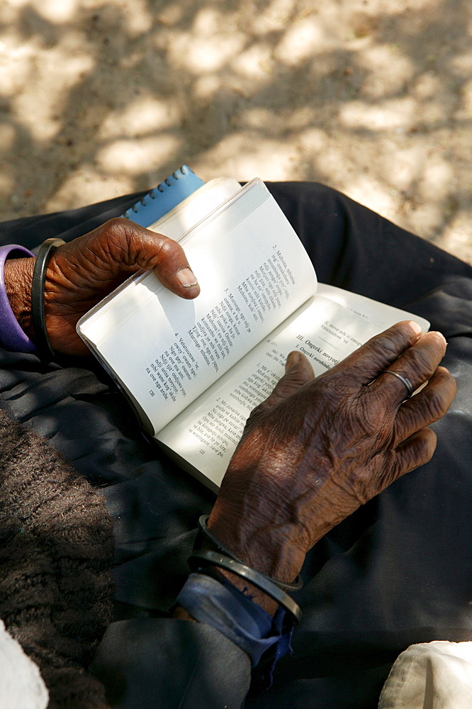 Elderly woman turning the pages of a hymnal, Sehitwa, Botswana, Africa