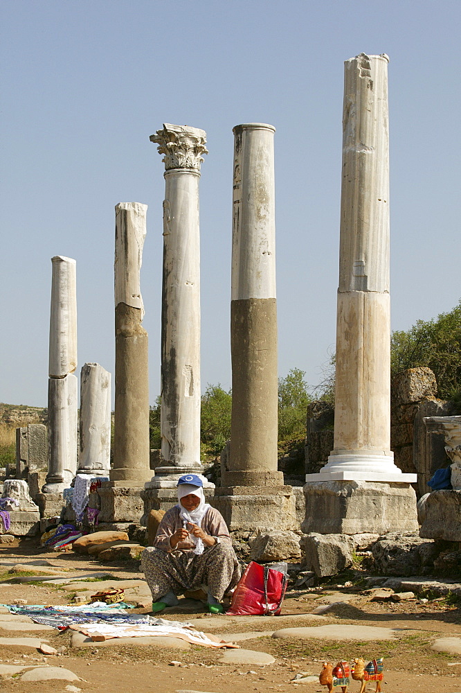 Woman crocheting blankets for tourists in front of the colonnade on the main street in Perga, Perge, southern Turkey, Asia