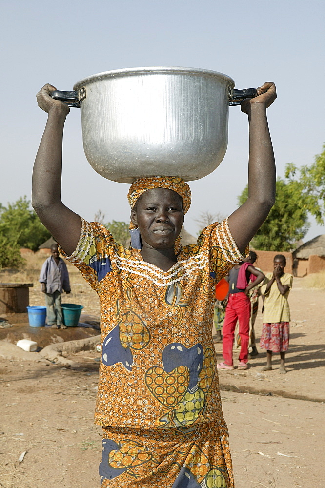 Woman carrying a pot of water on her head, well behind her, Pakete, Cameroon, Africa