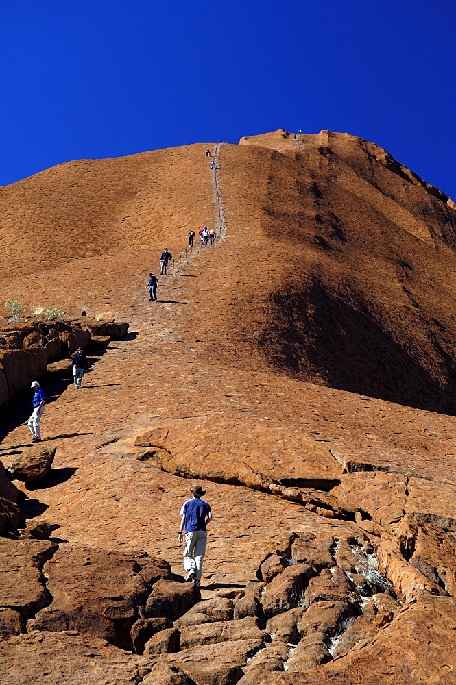 Tourists are climbing ayers rock, uluru, australia