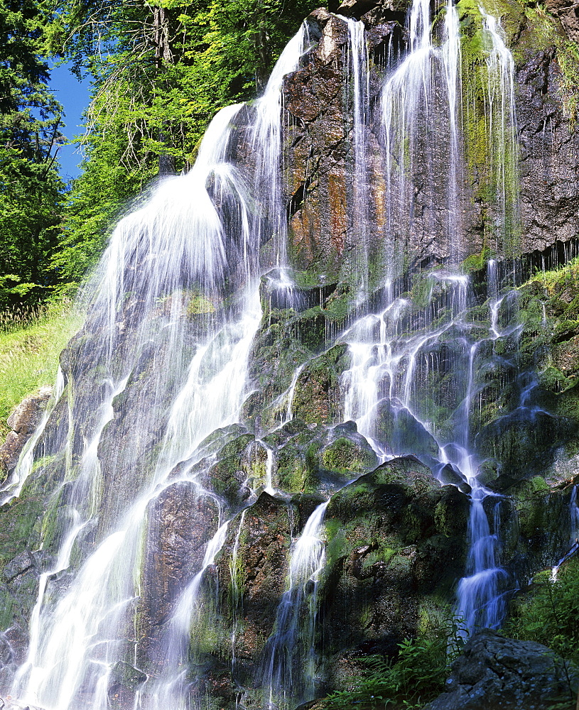 Waterfall in a mountain stream with moss-covered rocks. cascade