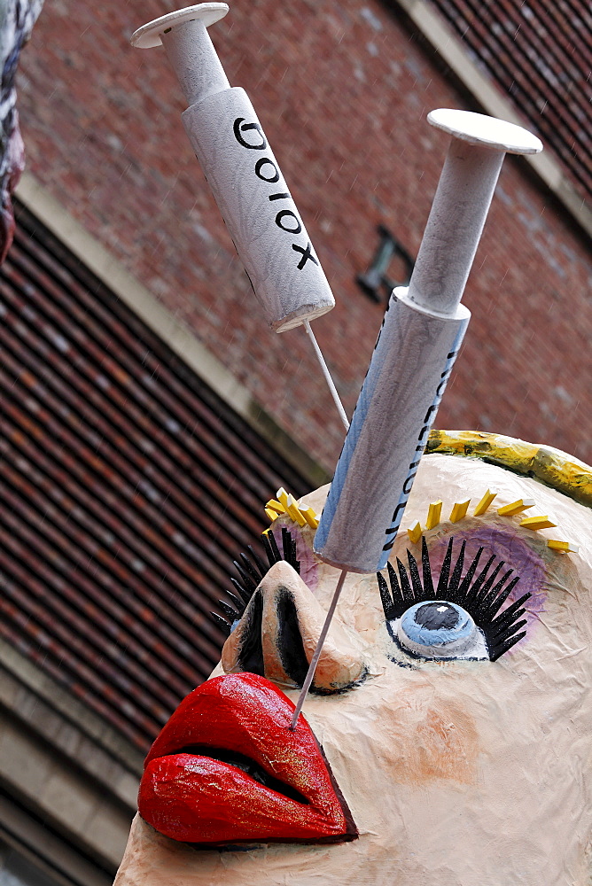 Paper-mache woman with collagen and botox needles sticking in her lips and face, Carnival (Mardi Gras) parade in Duesseldorf, North Rhine-Westphalia, Germany, Europe